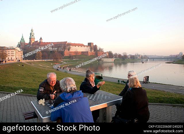 Nov 9, 2011. People playing outdoor chess on the Vistula boulevard. Royal Castle on the Wawel hill is visible at the background