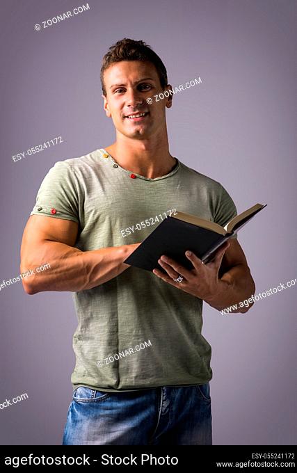Handsome Sexy Muscular Man Reading Book, on Grey Background