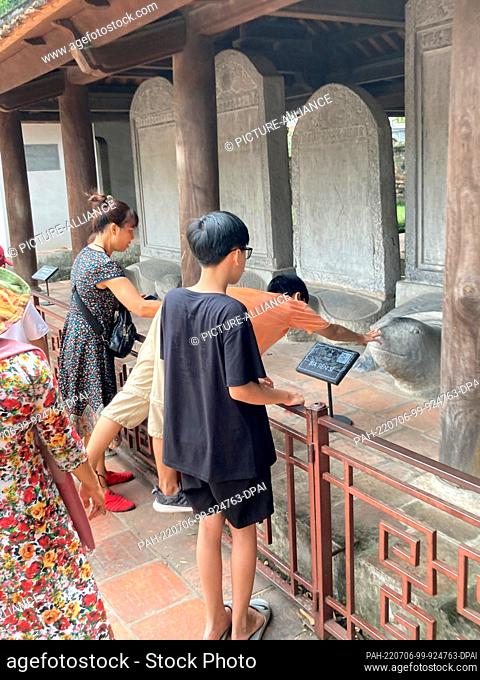 PRODUCTION - 29 June 2022, Vietnam, Hanoi: A boy tries to touch the head of one of the stone turtles at Vietnam's oldest elite university, Van Mieu-Quoc Tu Giam