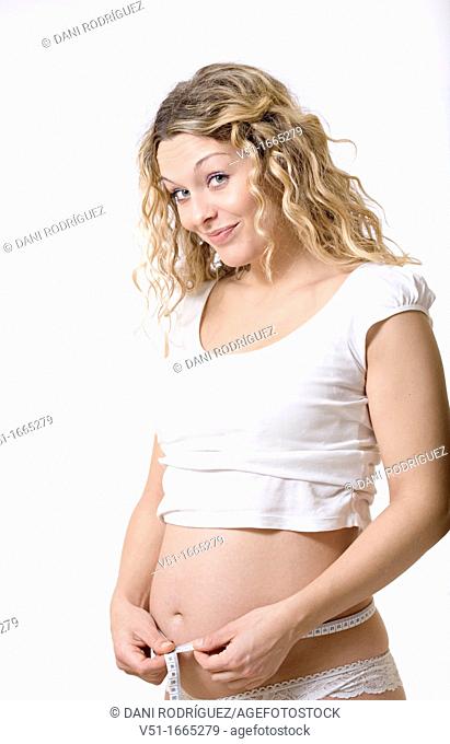 Blonde pregnant woman measuring her belly