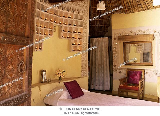 Raised mud reliefs inlaid with mirror on the walls in bedroom of modern home in traditional tribal Rabari round mud hut, Bunga style, near Ahmedabad