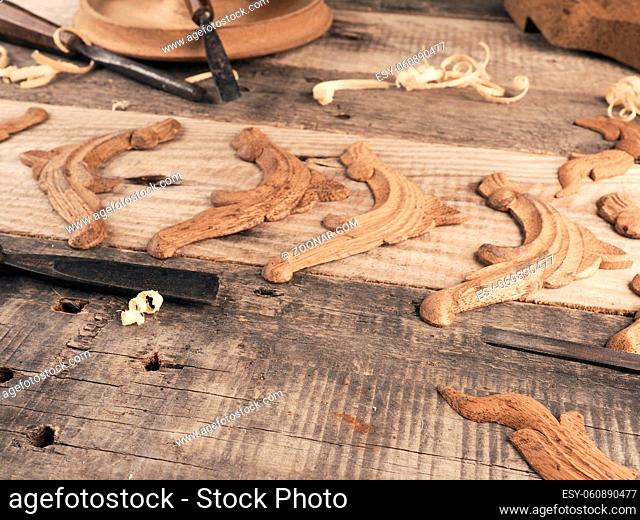 Carved oak decorative elements on a rustic workbench with chisels, wood working or creativity concept with space for text