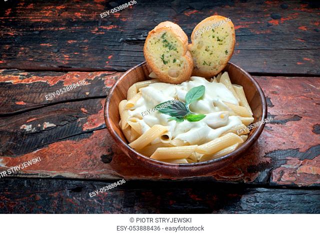 Four cheese pasta with garlic bread isolated on rustic wooden background