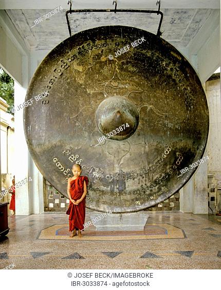 Novice standing in front of a huge bronze gong, Mahamuni Pagoda