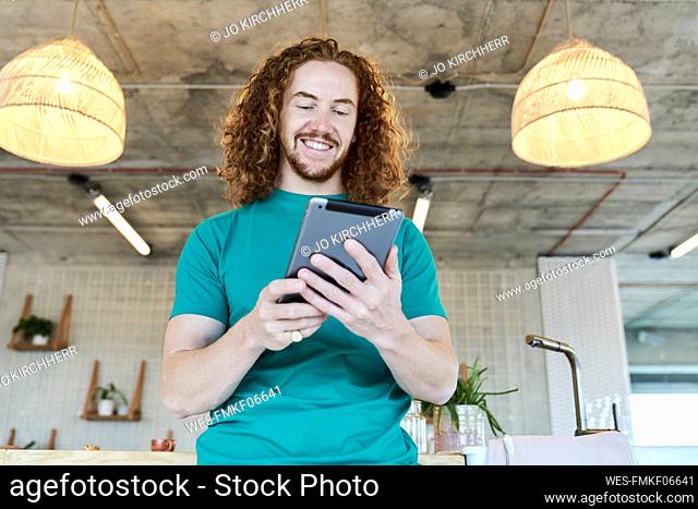 Handsome man holding digital tablet and smiling at home