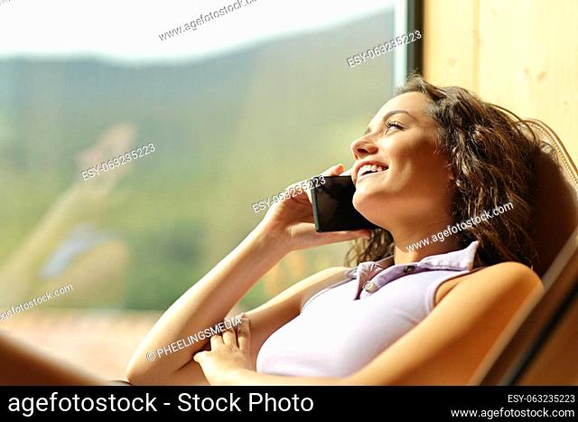 Happy woman on a chair talking on phone smiling