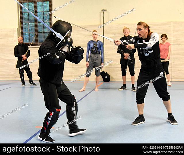 08 September 2022, Saxony, Leipzig: Historical fencing with long swords is practiced in a gym by fencing instructor Torsten Schneyer (r) with almost 20 members...