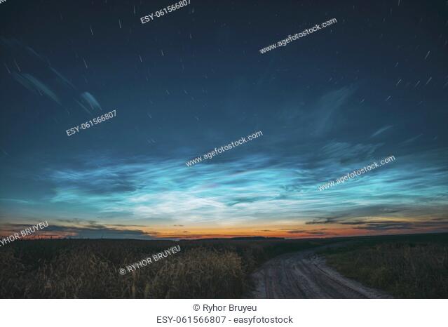 Amazing Rotate Stars Effect In Sky. Soft Colors. 6k Unusual Cloud And Stars Effects Above Countryside Rural Field Landscape With Young Wheat Sprouts