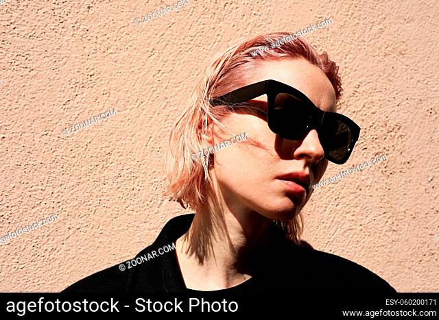 Headshot of young woman with pinkish hair, wearing sunglasses. High quality photo