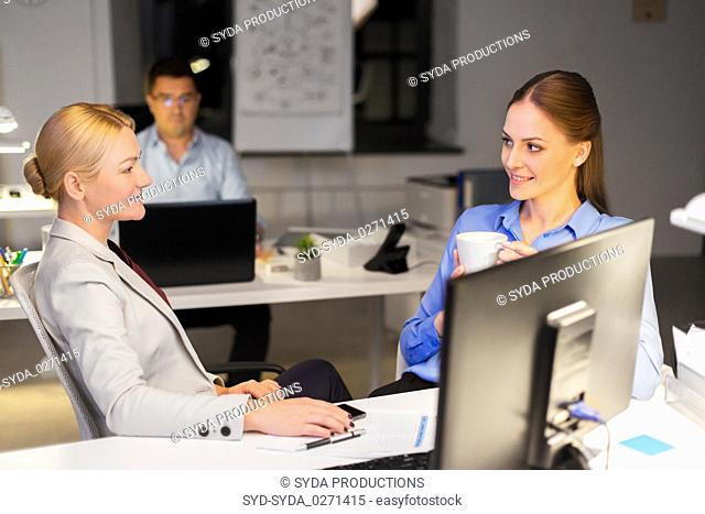 businesswomen drinking coffee at night office