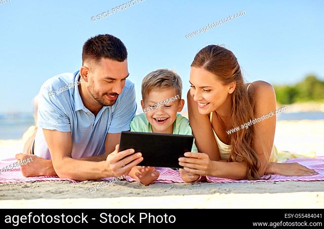 happy family with tablet computer on summer beach