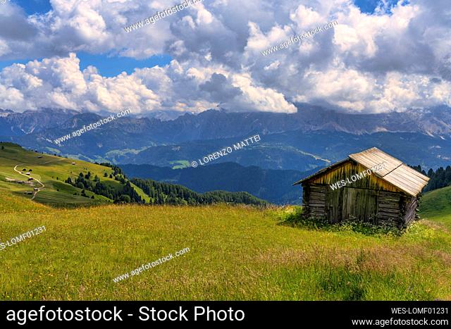 Dramatic clouds over lone hut at Odle mountain range during summer