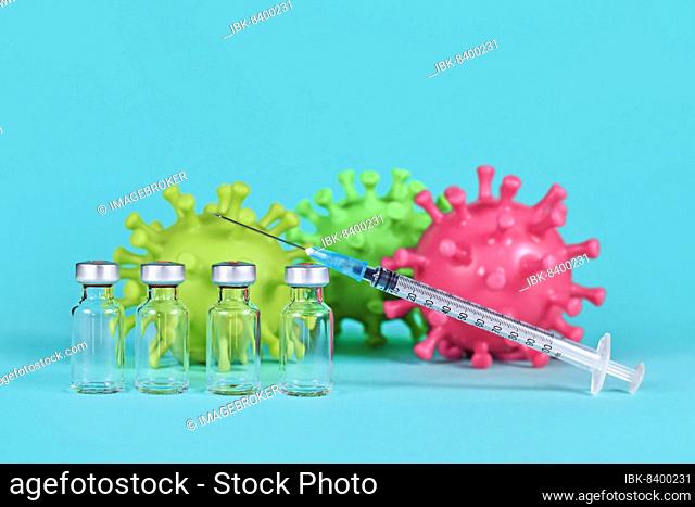 4 vaccine vials with syringes and corona virus models in background