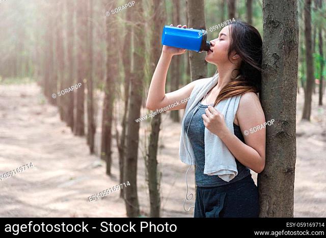 Sport beautiful young woman girl lifestyle exercise healthy drinking protein water after running workout in forest nature park with copy space