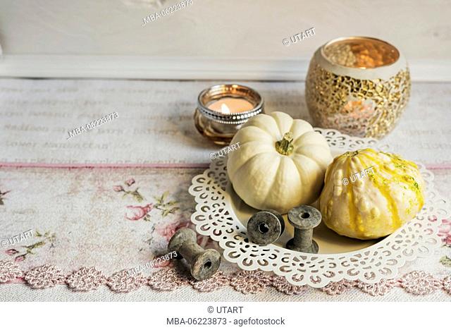 Autumnal still life with pumpkins in a white bowl, tea lights in background