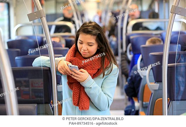 A young woman surfs the internet on her smartphone on a regional train on the line between Magdbeurg and Schoenebeck, Germany, 5 April 2017