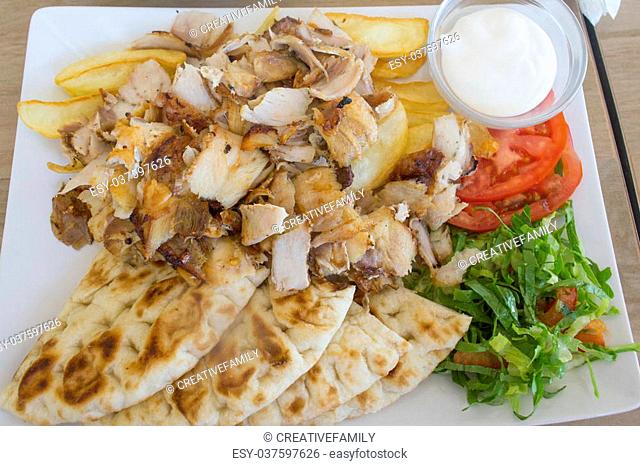 Chicken gyros portion with vegetables served on a plate offset