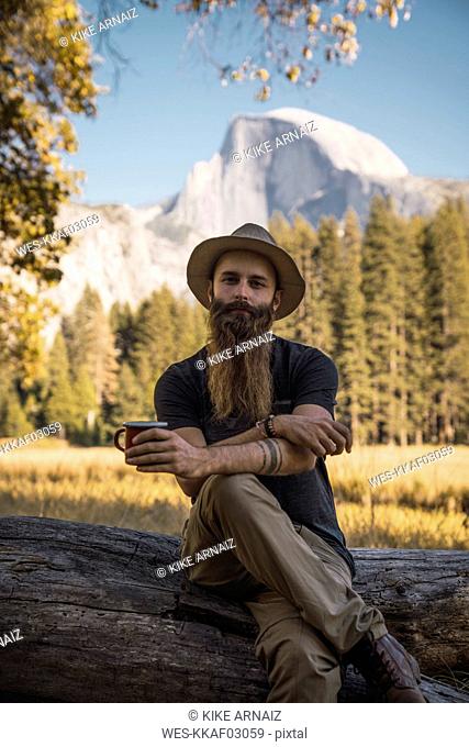 USA, California, portrait of bearded man sitting on a log in Yosemite National Park