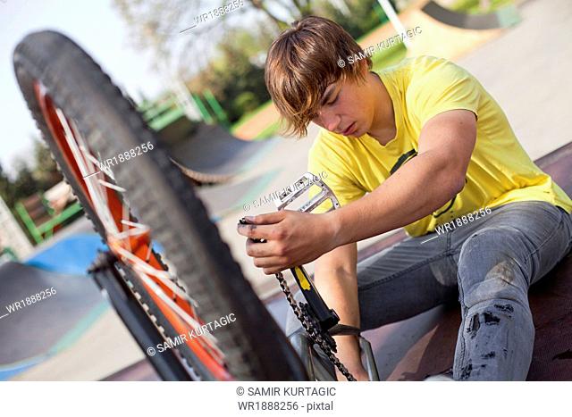 Teenager doing repair work on BMX bike, Osijek, Croatia, Europe