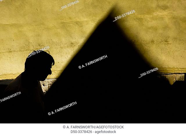 Syracuse, Sicily, Italy A man walks in a narrow alley on Ortygia island with a strong shadow