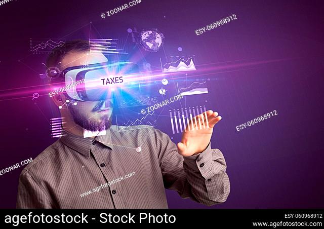 Businessman looking through Virtual Reality glasses with TAXES inscription, new business concept