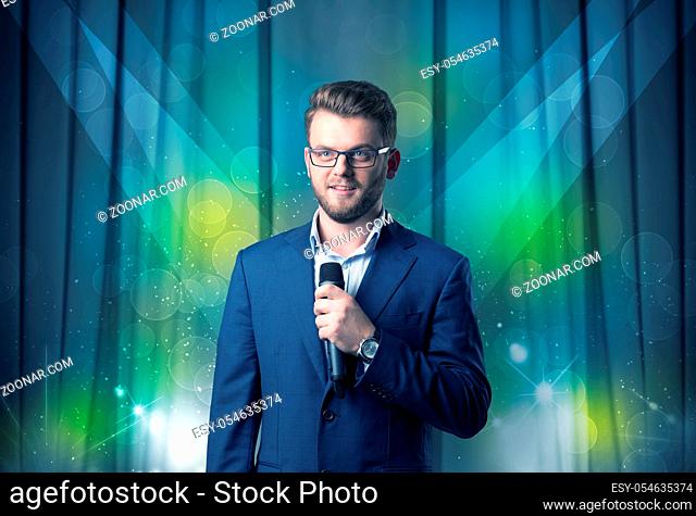 Businessman speaking into microphone with blue curtain behind him