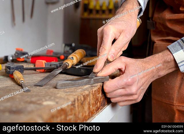 Carpenter sharpening a chisel. woodworking process with hand tools in a carpentry workshop. wood carving concept. High quality photography