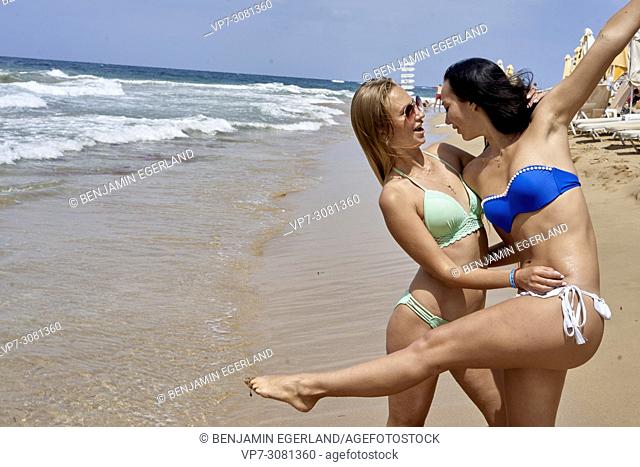 Two young women at beach in bikini. Malia, Crete, Greece