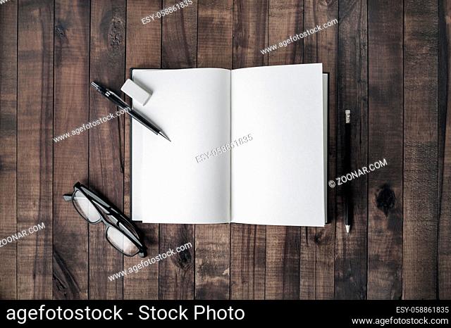 Blank book and stationery on wooden background. Opened notebook, glasses, pencil and eraser. Responsive design mockup. Flat lay