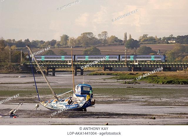 England, Essex, River Stour. A train crossing over the mudflats of the river Stour between Manningtree and Cattawade