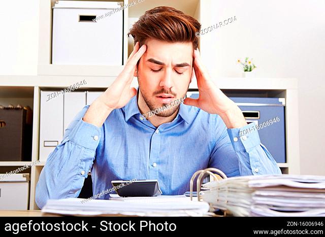 Geschäftsmann mit Burnout im Büro massiert seine schmerzenden Schläfen
