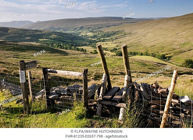 View of upland farmland and fells, with stile over drystone wall, looking down Dentdale from Whernside Pastures, Cumbria, England, july
