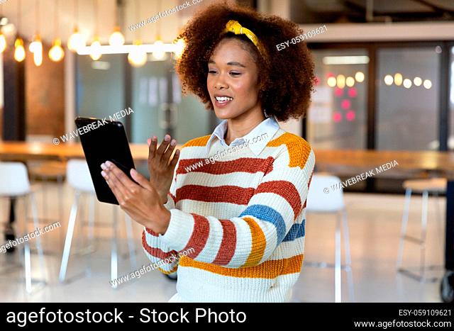 Portrait of mixed race smiling businesswoman standing having video using tablet