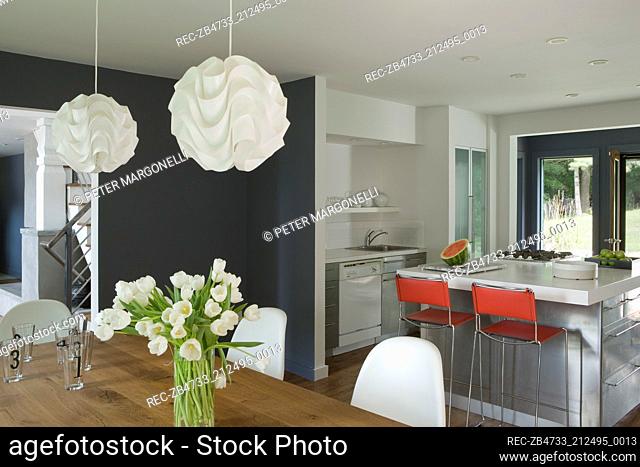 Bar stools at central island breakfast bar in spacious kitchen with dining area