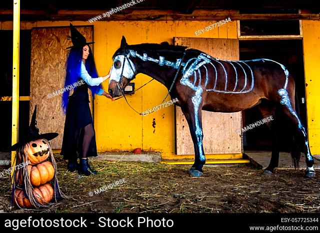A girl dressed as a witch took a horse out of a corral with a skeleton painted in white paint
