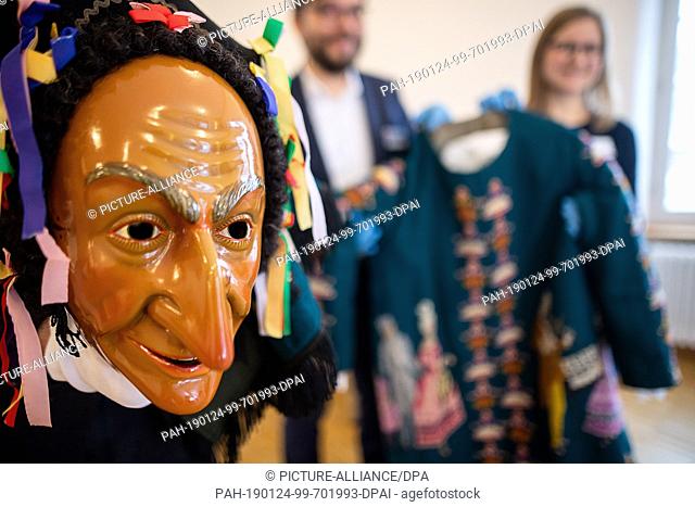 24 January 2019, Baden-Wuerttemberg, Waldenbuch: A man holds the larva of the fool's dress in his hand while handing over an original fool's dress
