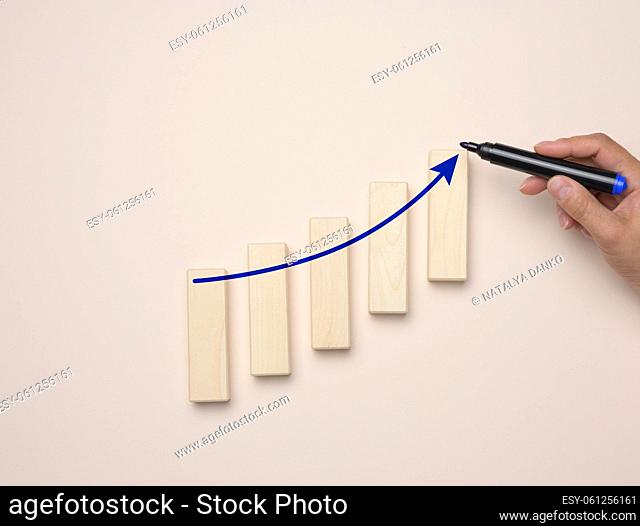 Graph with growing indicators and a female hand with a marker on a blue background. The concept of successful sales in business, inflation and rising prices