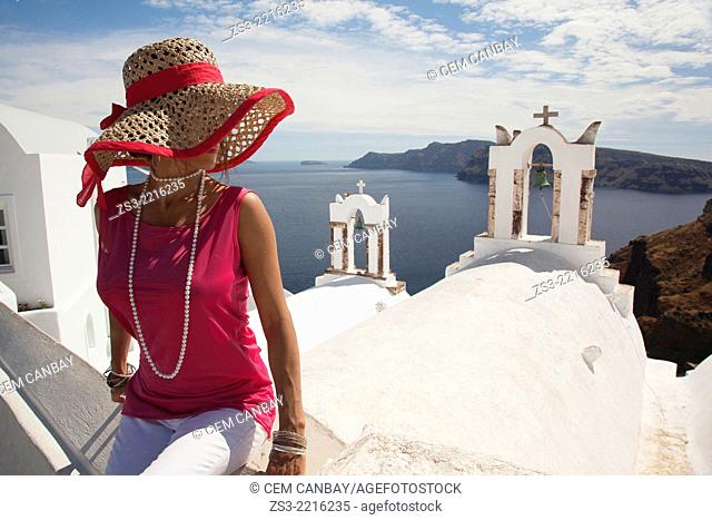 Woman in front of a bell tower in Oia town looking at Caldera, Santorini, Cyclades Islands, Greek Islands, Greece, Europe