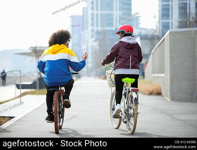 Teen friends riding bicycles on bike path in city
