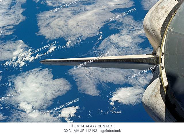 Backdropped by a blue and white part of Earth, space shuttle Discovery's vertical stabilizer and orbital maneuvering system (OMS) pods are featured in this...