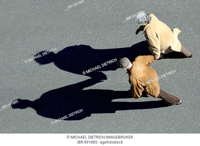 Senior couple walking hand-in-hand, bird's eye view with shadow