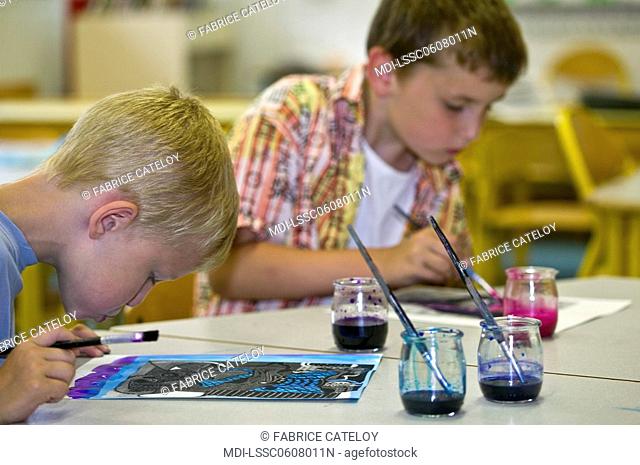 Two young boys painting in a school