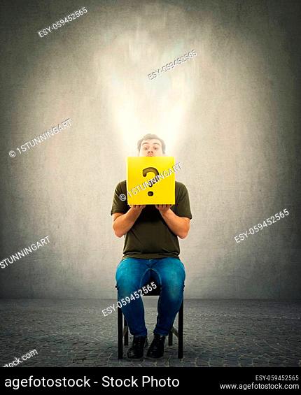 Curious man sitting on a chair looking cautious inside a mysterious yellow box as a magic light comes out. Unknown surprise concept as a question mark drawn on...