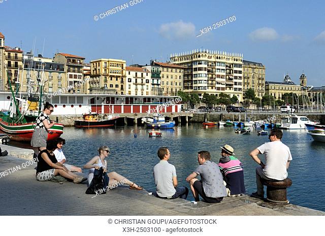 young people sitting on a quay at the port of San Sebastian, Bay of Biscay, province of Gipuzkoa, Basque Country, Spain, Europe