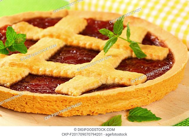 detail of strawberry jam tart with lattice on wooden cutting board