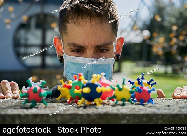 Caucasian guy with a protective mask and looking at virus models. The concept of Coronavirus