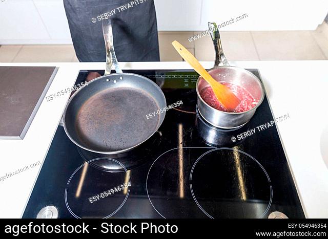 Close up of frying pan and pot with sauce on the stove
