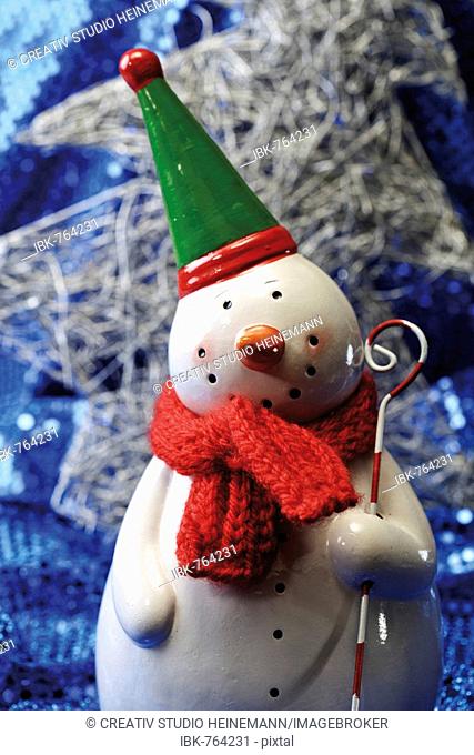 Snowman figurine wearing scarf on blue sequined material, Christmas decoration