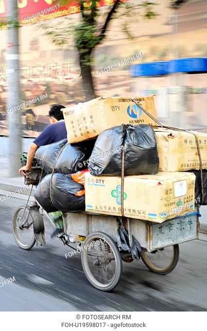 man male pedaling tricycle filled stacked boxes