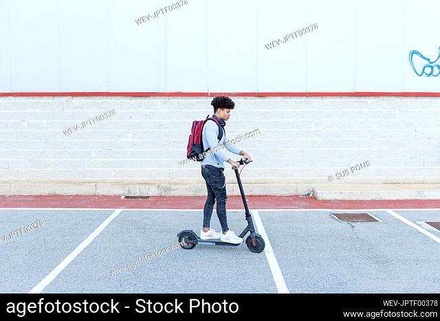 Young man riding e-scooter on parking deck
